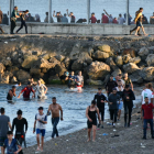 Personas migrantes caminan por la playa del Tarajal, en Ceuta.