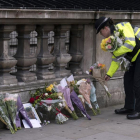 Una policia britànica diposita flors a prop del Parlament al costat d’un retrat de l’agent assassinat.
