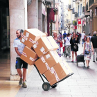 Un repartidor, com molts altres aquest dimarts, porta caixes en un carretó per repartir-les per les botigues.