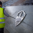 Un operario limpia con una manguera a presión los excrementos del escudo del palco del Camp d’Esports.