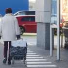 Una dona surt d’un supermercat amb el carret d’anar a comprar.
