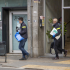 Dos agentes de los Mossos saliendo del número 80 de la avenida Alcalde Porqueres, donde fue hallado el cadáver.
