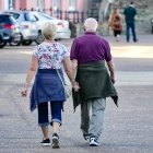 Una pareja de jubilados pasea por la calle.