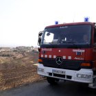 Un camió de Bombers a les proximitats del nucli de Guardiola, al municipi de Vilanova de l'Aguda, amb camps afectats per l'incendi de Torrefeta al fons.