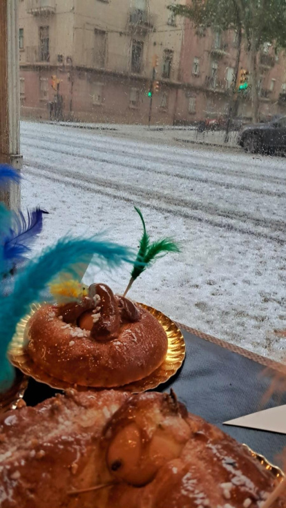 Fotografía tomada desde el interior del Forn i Pastisseria Llaràs, en Balàfia. En primer plano, una mona de Pascua y, al fondo, el estado en el que quedó la calzada con el granizo