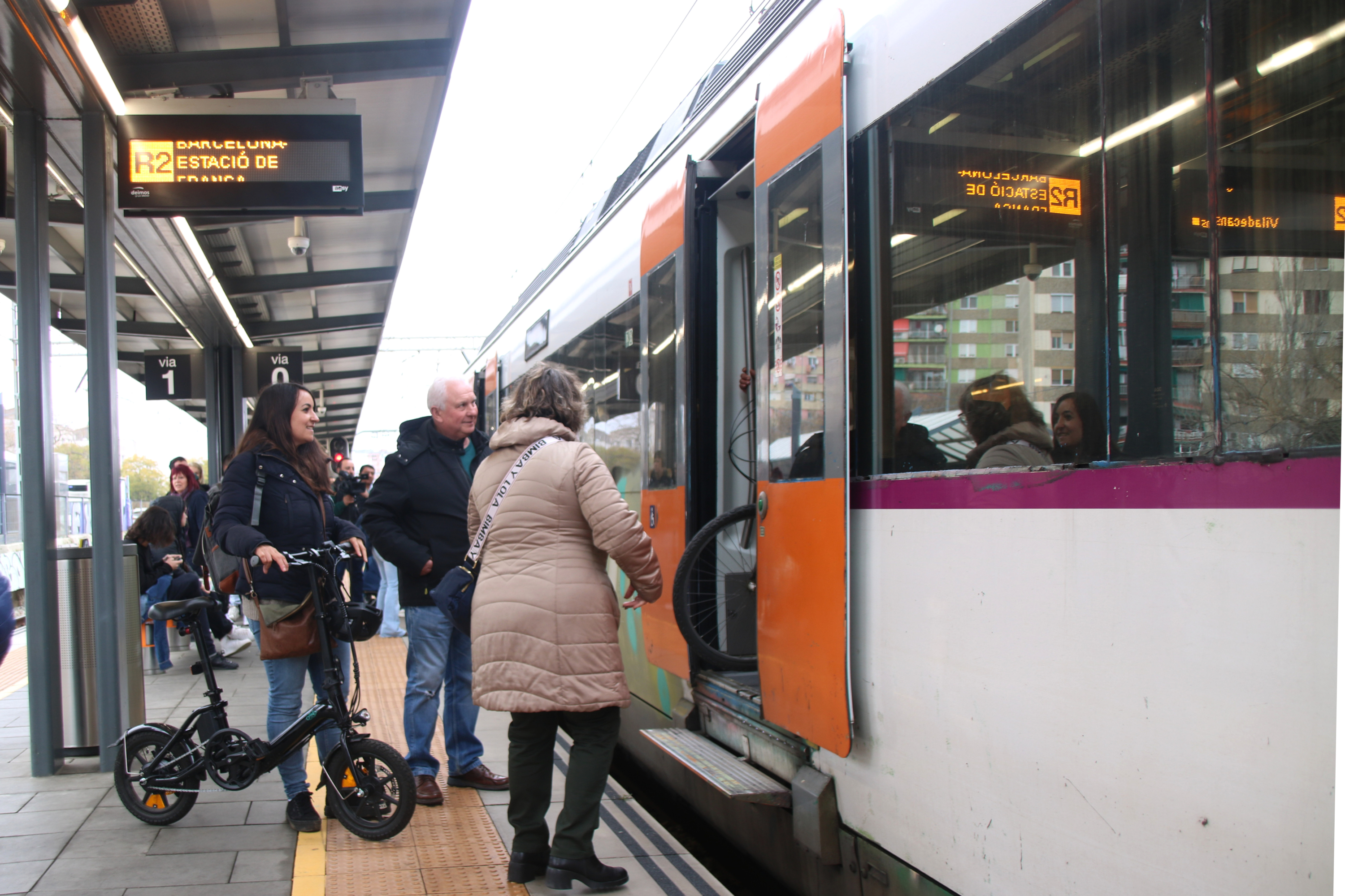 Vários passageiros subindo em um trem para a estação Bellvitge-Gornal que vai em direção a Barcelona.